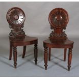 A pair of mid 19th century mahogany hall chairs, having a circular petallated back, waisted seat,