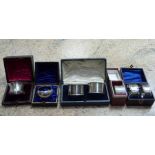 Two pairs of silver napkin rings, cased, together with three single napkin rings, cased,