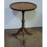 A mahogany stained small tripod table with circular pie crust top on turned column and three