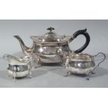 A George V boat shaped three piece silver tea service with gadrooned edge on shell cast scrolling