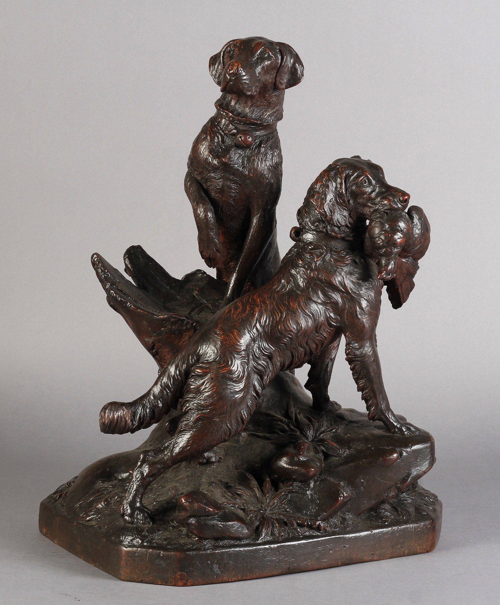 BLACK FOREST - A GOOD LINDEN WOOD CARVING OF TWO HUNTING DOGS, one with paw on a tree stump, the