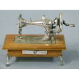 An Italian silver miniature sewing machine, foliate engraved and numbered 104507, wooden table