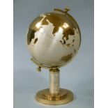 A globe shaped cigarette dispenser in brass