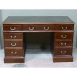 A reproduction mahogany pedestal desk having leather incised writing surface, three drawers across