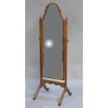 A walnut cheval mirror of arched outline, the uprights with urn finials