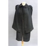 A Victorian black wool cape the fabric woven with leaves and having a broad trim detail to the