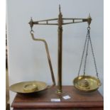 A set of brass balance scales on a mahogany plinth base with weights
