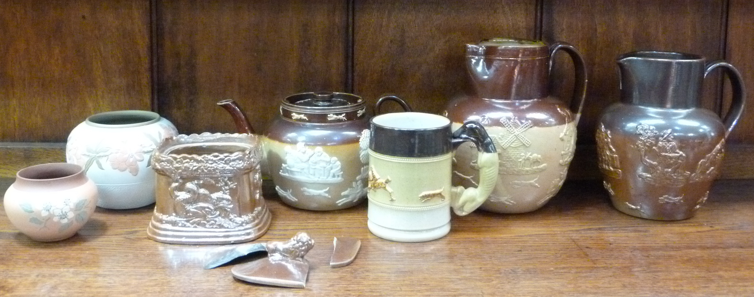 A Doulton Lambeth salt glazed jug, the upper section treacle brown, the lower section beige relief