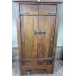 A rustic style two door wardrobe with one drawer below, with drop handles, black metal strap