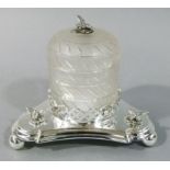 A silver plated and opaque glass honey pot on triangular stand, the pot cylindrical with domed