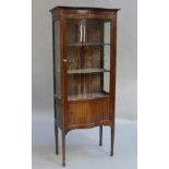 An Edwardian inlaid mahogany serpentine front display cabinet with glazed upper section and panelled