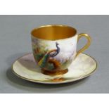 A Royal Worcester miniature cup and saucer painted with a peacock amidst pine branches by R