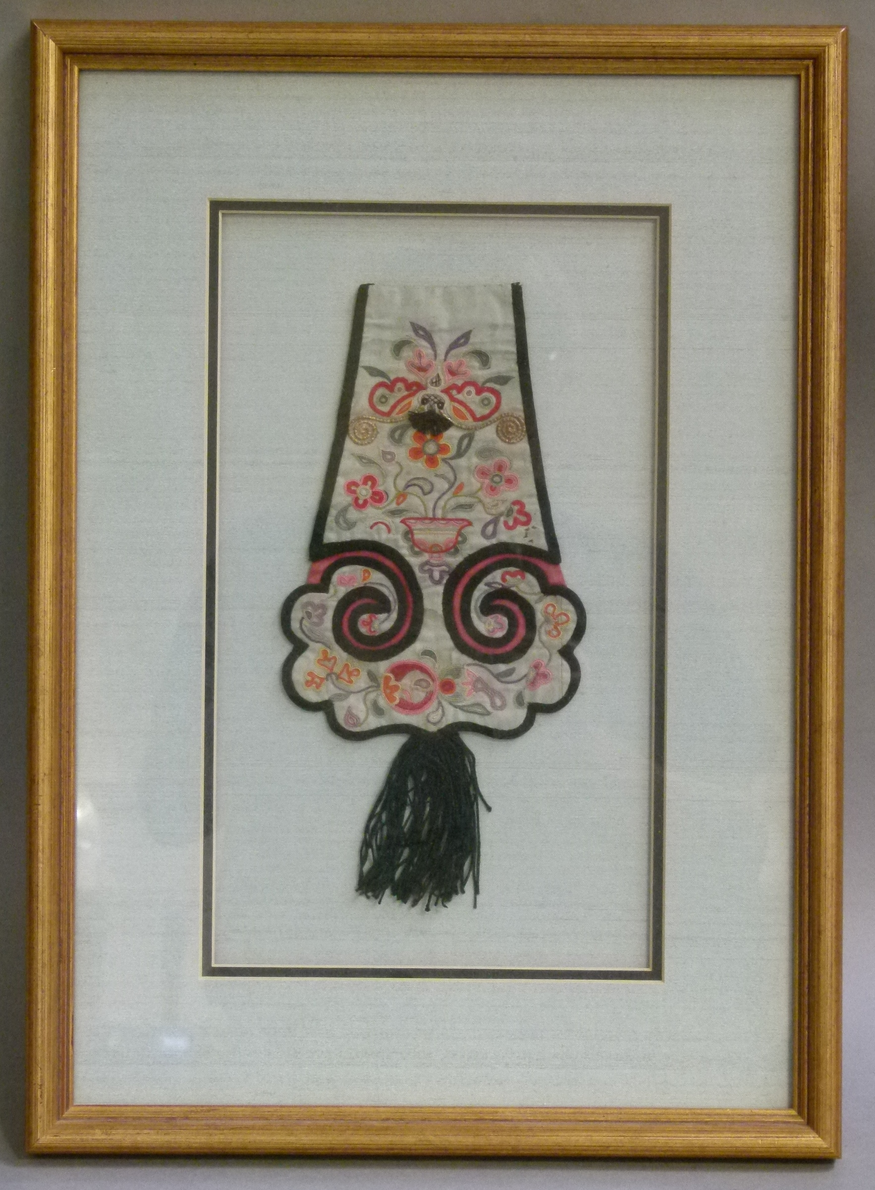 A Chinese silk embroidered hat flap with fringe c.1870 framed with pale blue mount