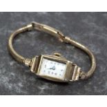 A lady's 9ct gold cased wristwatch on a 12ct rolled gold strap having a rectangular dial with Arabic