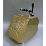 An arts and crafts brass coal bin with ebonised turned handle, the hinged front embossed with