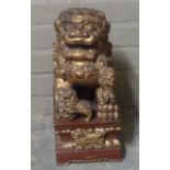 A reproduction carved wooden dog of fo, seated on a rectangular base carved with borders and further