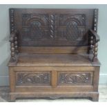 An oak monks bench with folding carved top on bobbin turned supports, hinged seat above a twin