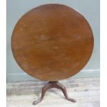 A George III mahogany tripod table the circular top above a vasular turned column and three outswept