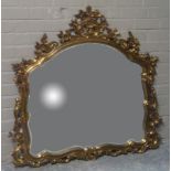 A reproduction gold painted plaster wall mirror with ornate foliate and scroll cast frame, 116cm