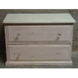 A pine two drawer chest painted in cream and pink, one handle missing, plinth base