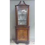 An Edwardian mahogany standing corner cupboard in Sheraton style with swan neck pediment above