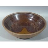 A large studio pottery bowl the centre with stylised flowerhead in brown and caramel glazes, 40cm