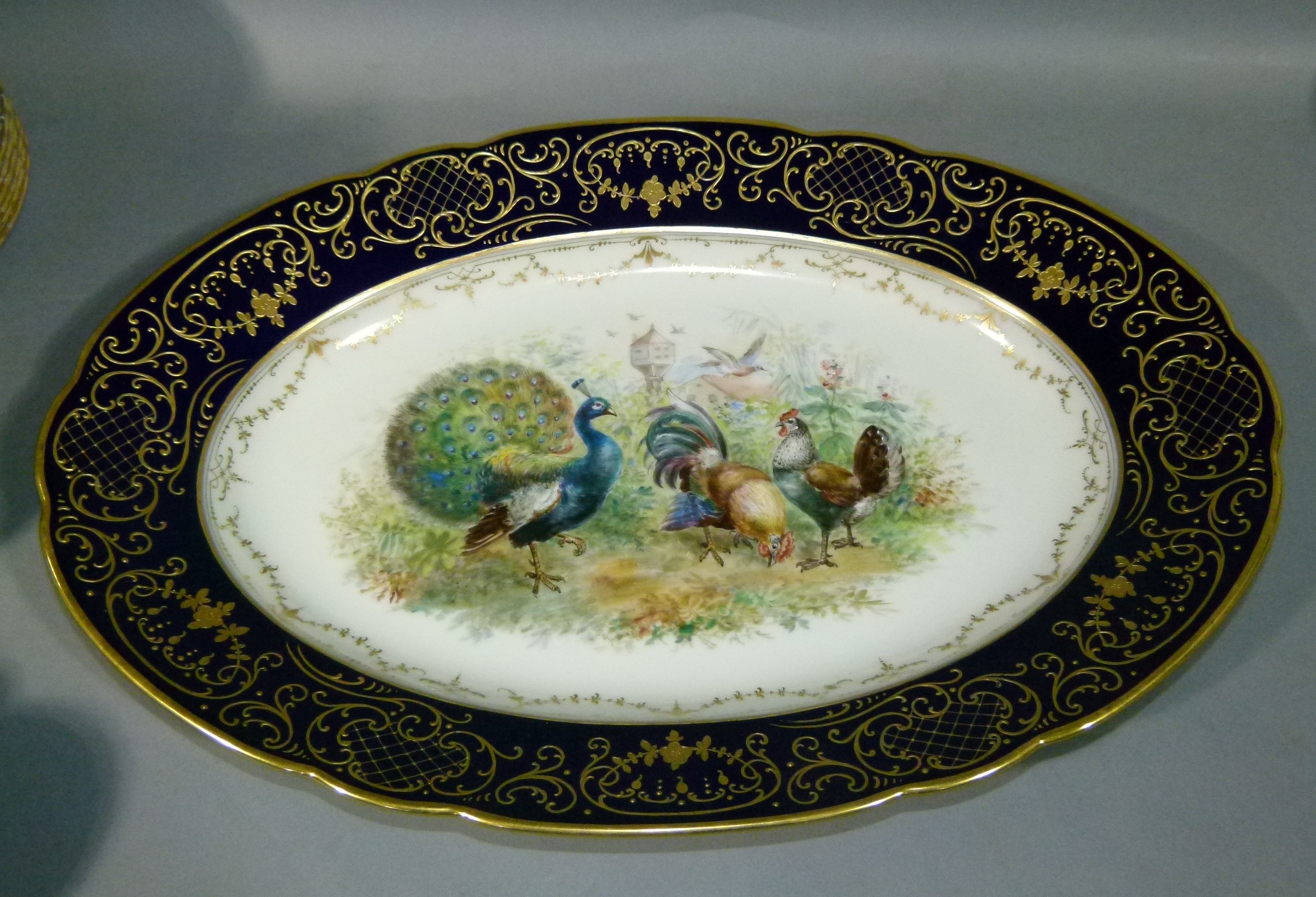 A Dresden porcelain oval meat platter, the centre painted with chickens, cockerel and peacock with