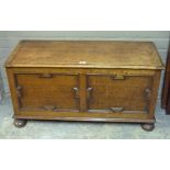 A 1920's oak ottoman having hinged lid over two indented panels with Jacobean style moulding and