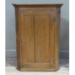 A 19th century oak hanging corner cupboard with single indented panel door, the interior painted