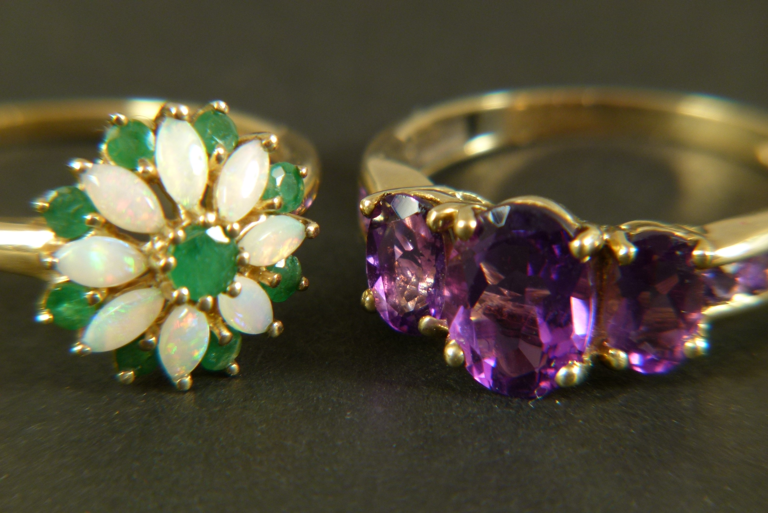 An amethyst dress ring, three graduated oval faceted stones claw set in line flanked by channel