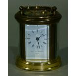 A brass cased oval carriage time piece with swing handle, the white enamel face inscribed Matthew