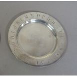 A circular silver dish with shallow dished centre, the border engraved with the alphabet, 16cm