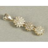 A diamond cluster pendant, the eight cut stones claw set to each of three graduated clusters on a