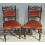 A pair of Edwardian walnut dining chairs having a floret carved and spindle top rail above an