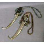 Two ornamental curved blade daggers with white metal sheaths and with silk cords