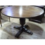 An oak pedestal dining table with extra leaf on cruciform base