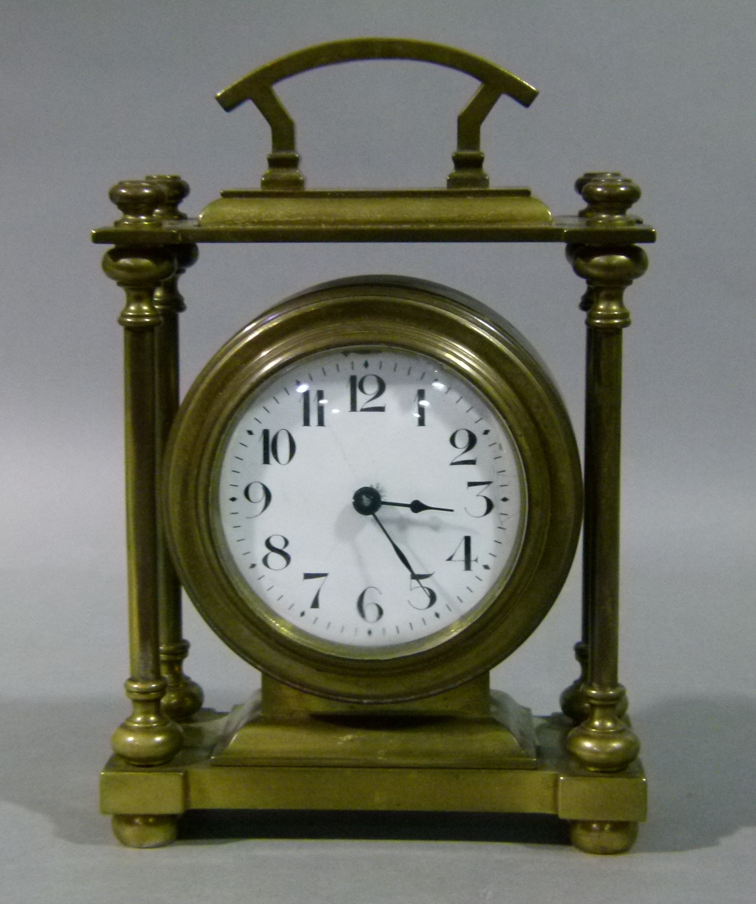 A brass cased mantel clock with fixed carrying handle, the circular drum case contained within