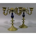 A pair of Continental porcelain and brass two branch candelabrum, the blue pottery baluster stems