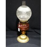 A Circular Based Brass Column Oil Lamp With Cranberry Tinted Reservoir