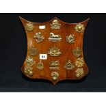 A Wooden Shield Plaque With A Collection Of Mixed Regimental Badges