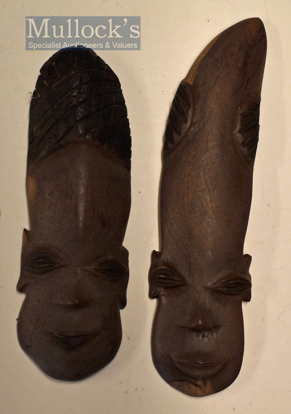 Pair of Biafran (Nigerian Tribe) male genitalia masks in carved and part stained hardwood (used as a