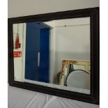 LARGE STAINED OAK FRAME MIRROR with inset leather panels with decorative stitching, encasing a