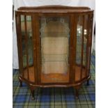 1950'S WALNUT BOW FRONT DISPLAY CABINET with a raised back above a glazed central door flanked by