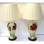 PAIR OF MOORCROFT POTTERY TABLE LAMPS with a cream ground and decorated with frilled orchids,