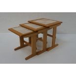 NEST OF THREE OAK TILE-TOP TABLES raised on shaped ends with stretchers, the largest 44.8cm wide
