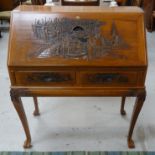 MALAYSIAN TEAK BUREAU on a stand, with a carved fall flap and sides above two carved frieze