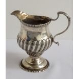 GEORGE III SILVER CREAM JUG with gadrooned decoration to the body and a beaded rim, London hallmarks