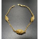 TWENTY-ONE CARAT GOLD BRACELET with three pierced elliptical links separated by chain sections,