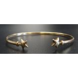 NINE CARAT GOLD BANGLE with star finials, approximately 2.7 grams