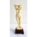 EARLY 20th CENTURY IVORY CARVING OF A NUDE LADY with both hands in her hair, raised on a shaped
